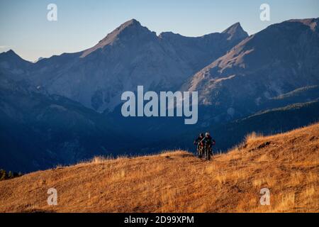 Zwei Männer fahren eBikes bei Sonnenuntergang im Queyras Natural Regional Park in der Region Hautes-Alpes in Frankreich. Mountainbiken, Alpen Stockfoto