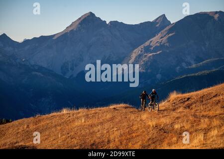 Zwei Männer fahren eBikes bei Sonnenuntergang im Queyras Natural Regional Park in der Region Hautes-Alpes in Frankreich. Mountainbiken, Alpen Stockfoto