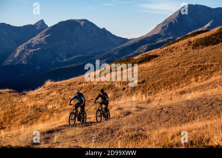 Zwei Männer fahren eBikes bei Sonnenuntergang im Queyras Natural Regional Park in der Region Hautes-Alpes in Frankreich. Mountainbiken, Alpen Stockfoto