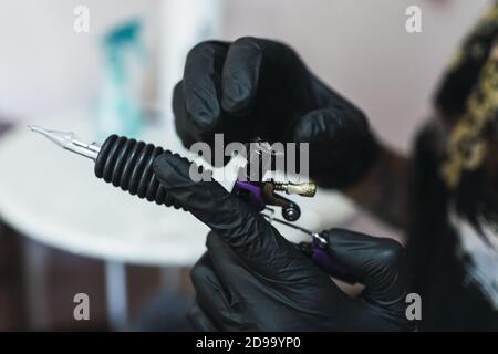 Tattoo Künstler trägt schwarze sterile Handschuhe und hält ein Tattoo Stift Stockfoto