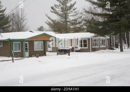 Schneebedeckte Häuser in Prudenville in der Nähe des wunderschönen Lake Michigan im Winter Stockfoto