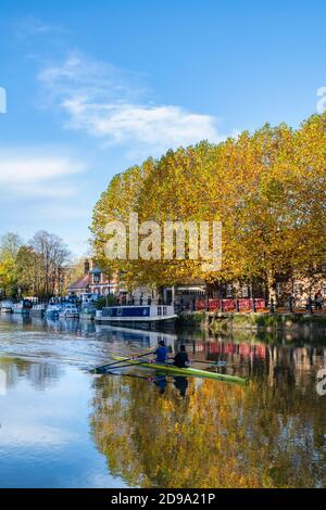 Narrowboat und Ruderer auf der themse bei St. Helens Wharf bei Sonnenaufgang im Herbst. Abingdon on Thames, Oxfordshire, England Stockfoto