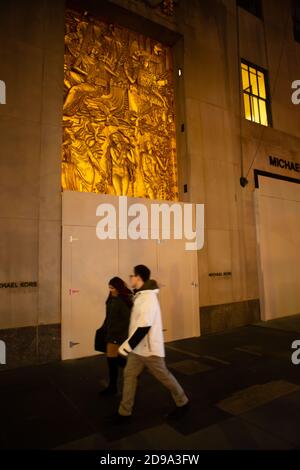 New York, NY, USA. November 2020. New York City erwartet die Ergebnisse der Präsidentschaftswahlen, da die Umfragen in einigen Staaten schließen. Ein Paar geht an dem vernagelten Michael Kors-Laden im Rockefeller Center vorbei. Kredit: Ed Lefkowicz/Alamy Live Nachrichten Stockfoto