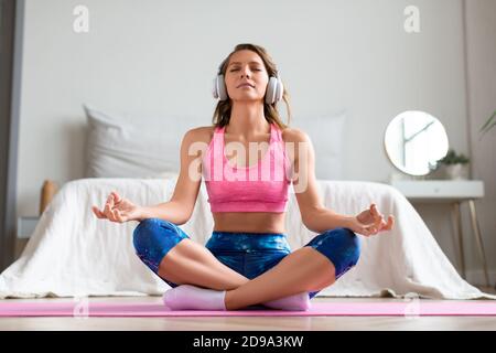 Yoga zu Hause - Ganzkörperporträt einer Frau mit geschlossenen Augen in Lotusposition. Vorderansicht. Stockfoto