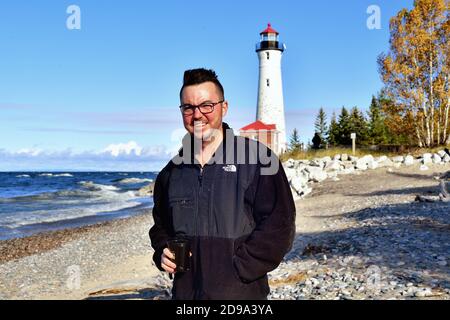 Paradise, Michigan, USA. Lächelnder Mann, der sich am Strand an einer abgelegenen, abgelegenen Küstenlinie entlang des Lake Superior auf der Upper Peninsula entspannt. Stockfoto