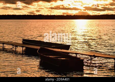 Forelle Lake, Michigan, USA. Ein paar verbleibende Wolken stumm die späte Nachmittagssonne, wie es auf die Oberfläche des Sees über ein Paar Ruderboote reflektiert. Stockfoto