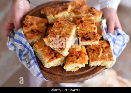 Weibliche Hände halten frisch gebackenes Brot / hausgemachte italienische Focaccia mit Rosmarin und Olivenöl Stockfoto