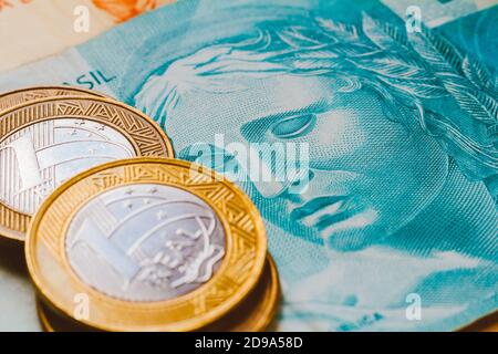 In dieser Fototafel werden die echten Münzen auf die brasilianische Banknote in goldenem Ton gelegt. Stockfoto