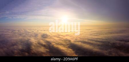Drohnenflug über den Nebel. Orangefarbene Morgensonne, Strahlen beleuchten den dichten Nebel Stockfoto