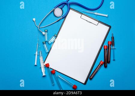 Zwischenablage mit leerem Blatt Papier mit medizinischen Werkzeugen auf Blauer Hintergrund mit Cope Space Stockfoto