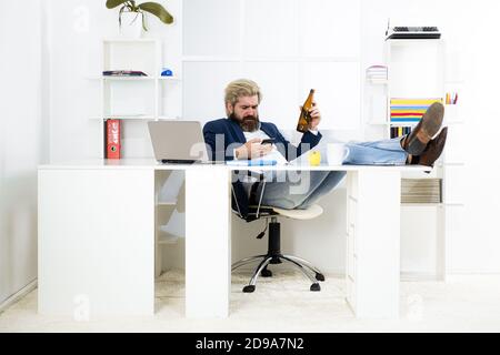 Müde gelangweilte Geschäftsmann Gähnen am Arbeitsplatz in der Nähe von Laptop, langweilige Arbeit, Sackgasse Job, Überarbeit extra nach Stunden, Alkohol trinken. Geschäftsmann trinkt Stockfoto