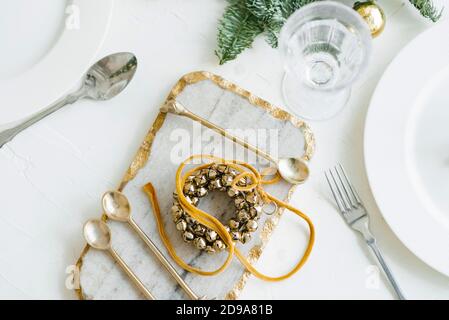 Weihnachtskranz der Goldenen Glocken in der Dekoration des festlichen Abendessens. Besteck auf einem Marmorbrett Stockfoto