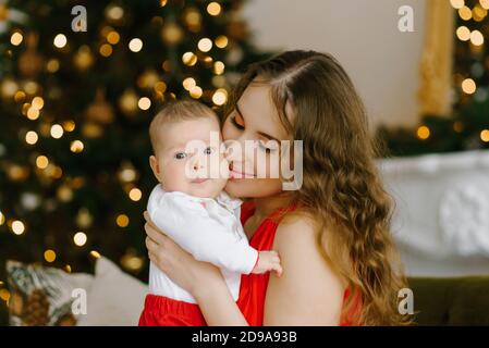 Frohe Weihnachtsfeier einer jungen Mutter und eines kleinen Sohnes Im Wohnzimmer am Weihnachtsbaum Stockfoto