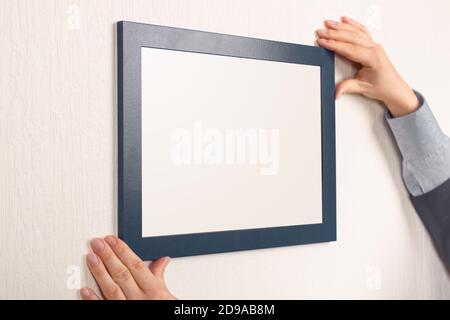 Mockup Diplom. Frau hängen Fotorahmen mockup an der Wand. Zertifikat, Diplom, Bild, Dankbarkeit weißen Rahmen mockup. Gradient im Rahmen Stockfoto