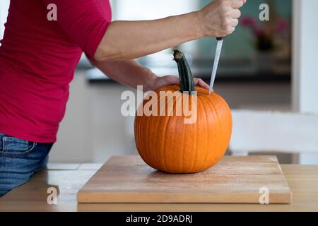 Eine Frau, die halloween-Kürbis auf einen Tisch im Wohnzimmer schnitzt Stockfoto