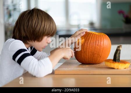 Ein Junge, der halloween-Kürbis auf einen Tisch im Wohnzimmer schnitzt Stockfoto