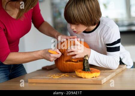 Mutter und Sohn schnitzen halloween-Kürbis im Wohnzimmer Stockfoto