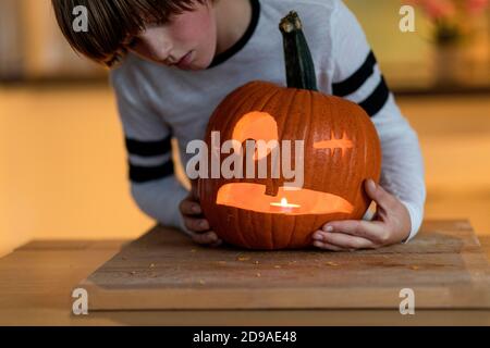 Der Junge schnitzte Halloween-Kürbis und steckte ein Kerzenlicht hinein Stockfoto