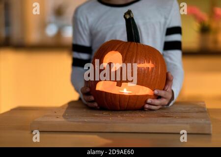 Der Junge schnitzte Halloween-Kürbis und steckte ein Kerzenlicht hinein Stockfoto