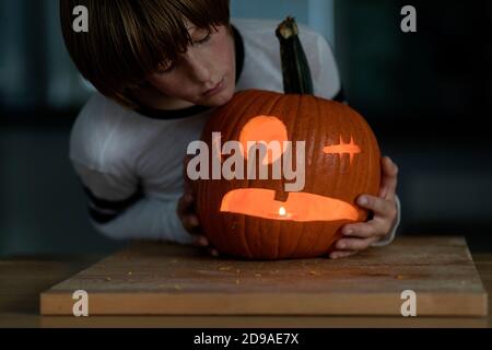 Der Junge schnitzte Halloween-Kürbis und steckte ein Kerzenlicht hinein Stockfoto