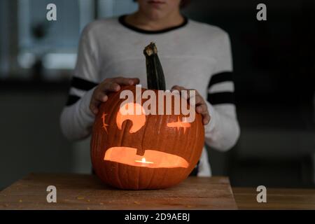 Der Junge schnitzte Halloween-Kürbis und steckte ein Kerzenlicht hinein Stockfoto