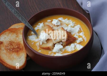 Kürbiscremesuppe mit Feta-Käse, herbstliche hausgemachte Speisen, dunkler Holzhintergrund. FODMAP-Diät, vegetarische Menü, sauberes Essen Rezept. Stockfoto