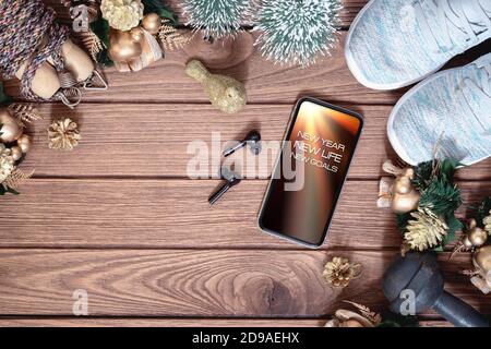 Neujahrsvorsätze gesunde Ziele Hintergrundkonzept. Neues Jahr Neues Leben Neue Ziele Text auf Handy auf dem Tisch mit Sportschuhen, schnurlose Kopfhörer, Stockfoto