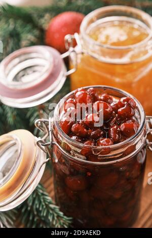 Nahaufnahme eines Orangen- und Dogwood Konfitüren Gläser auf einem Holztisch mit Apfelstrudel im Hintergrund Stockfoto