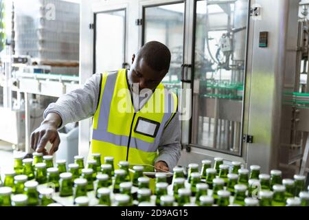 Afroamerikanischer Arbeiter Mann in einer Brauerei und Flaschen von Bier Stockfoto