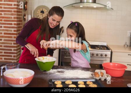 Kaukasische Frau mit ihrer Tochter Backen in einer Küche und Schürze tragen Stockfoto