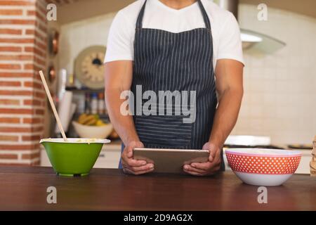 Kaukasischer Mann, der in einer Küche steht und Schürze trägt Stockfoto