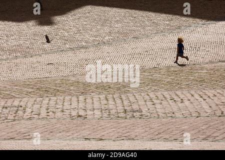 Ein kleines Kind, das eine Taube auf der Piazza del Campo, Siena, Toskana, Italien, jagt Stockfoto