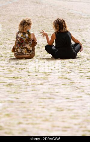 Zwei Frauen sitzen und sprechen auf der Piazza del Campo, Siena, Toskana, Italien Stockfoto