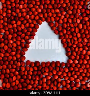 Weißes Dreieck von negativem Raum in einem Hintergrund von glänzenden roten Perlen erstellt. Stockfoto