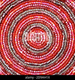 Makro-Bild von kleinen glänzenden irisierenden rosa Glasperlen in einem Muster von konzentrischen Kreisen genäht. Stockfoto