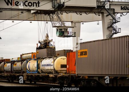 Kranladen und Entladen von Transportbehältern auf einem Zug in Die Wiener Donau Hafengebiet Stockfoto