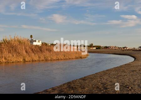 Kleiner Fluss Entspannen Sie sich vor der Flussmündung ins Tyrrenische Meer. Ruhe und Gelassenheit. Landschaftlich reizvolle Farben. Weiße Hütte, die aus einem dichten Schilf hervortritt. Stockfoto