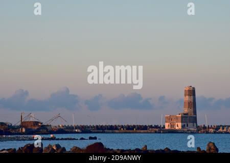 Alte zerstörte Leuchtturm und alte Fischerhütten in einer Lagune an der Küste in der Nähe von Rom, Italien Stockfoto