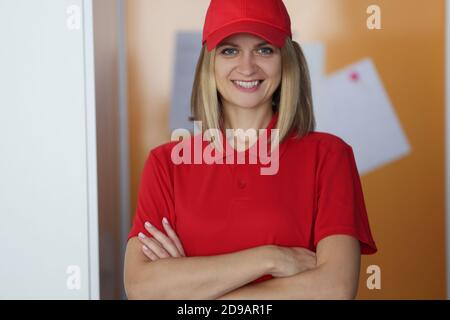 Frau Kurier in Uniform steht und lächelt mit gefaltet Arme Stockfoto