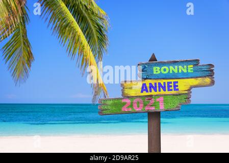 Bonne annee 2021, bedeutet glückliches neues Jahr auf Französisch, auf Richtungszeichen, tropischer Strand Hintergrund Stockfoto