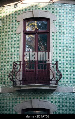 Ein Fragment der Fassade eines typischen Gebäudes mit einem Fenster und portugiesischen traditionellen Azulejo Fliesen. Porto, Portugal. Stockfoto