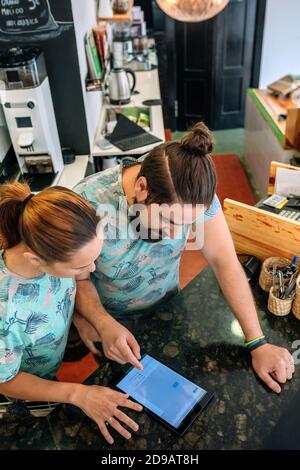 Draufsicht auf die Besitzer eines Coffee Shops, die arbeiten und suchen Am Tablet Stockfoto