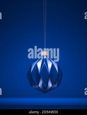 Hängende glänzende königsblaue Weihnachtskugel mit modernen geometrischen Muster. Lichtreflexionen. Weihnachtsdekoration, festliches Atmosphärenkonzept. Stockfoto