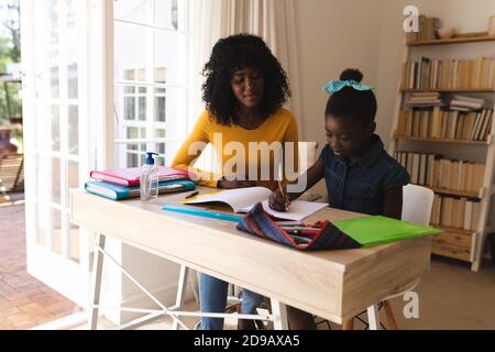 afroamerikanische Mutter hilft Tochter mit Hausaufgaben während sitzen auf Stühle zu Hause Stockfoto