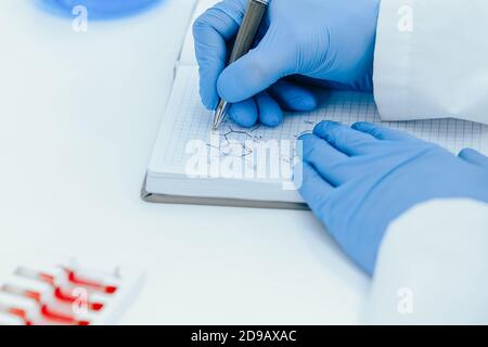 Nahaufnahme. Wissenschaftler Virologe Aufzeichnung der Testergebnisse in einer Zeitschrift. Stockfoto