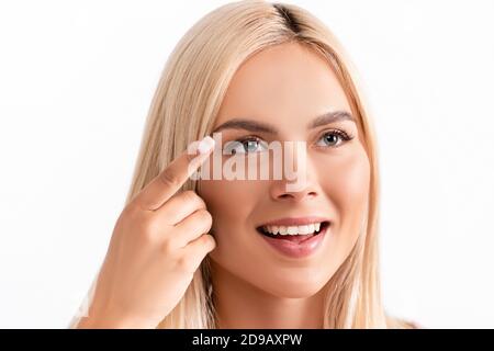 Positive blonde Frau hält Kontaktlinse isoliert auf weiß Stockfoto
