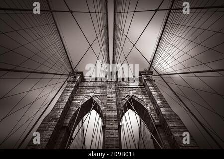 Dramatisches Bild der Brooklyn Bridge in NYC, USA. Alte Fotostilisierung, Filmkörnung hinzugefügt. Sepia getönte Stockfoto