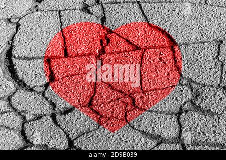 Rotes Herz auf einer gesprungenen Textur. Das Konzept des gebrochenen Herzens, Ende der Liebe und Enttäuschung. Stockfoto