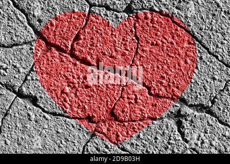 Rotes Herz auf einer gesprungenen Textur. Das Konzept des gebrochenen Herzens, Ende der Liebe und Enttäuschung. Stockfoto