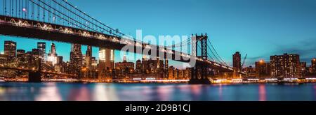 Manhattan Skyline und Manhattan Bridge bei Nacht. Die Manhattan Bridge ist eine Hängebrücke, die den East River in New York City überquert Stockfoto